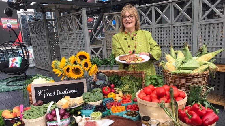 A woman stands in front of a table full of produce