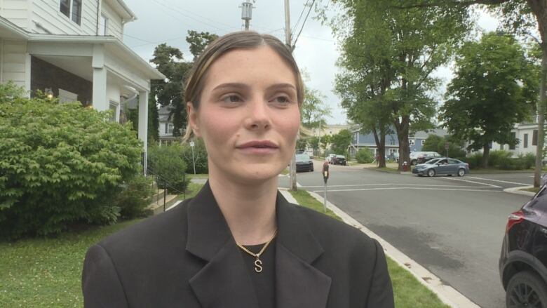 A white woman with her hair pulled back wearing a black top and black blazer