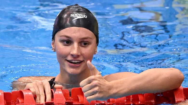 A women's swimmer gives a thumbs up after a race.