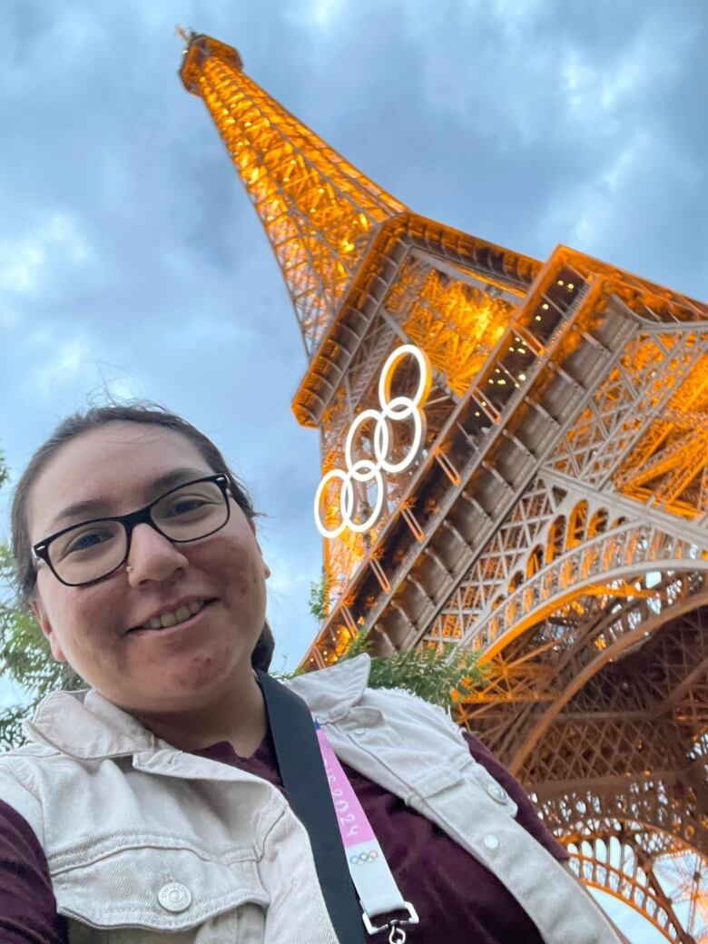 A journalist smiling in front of the Eiffel Tower