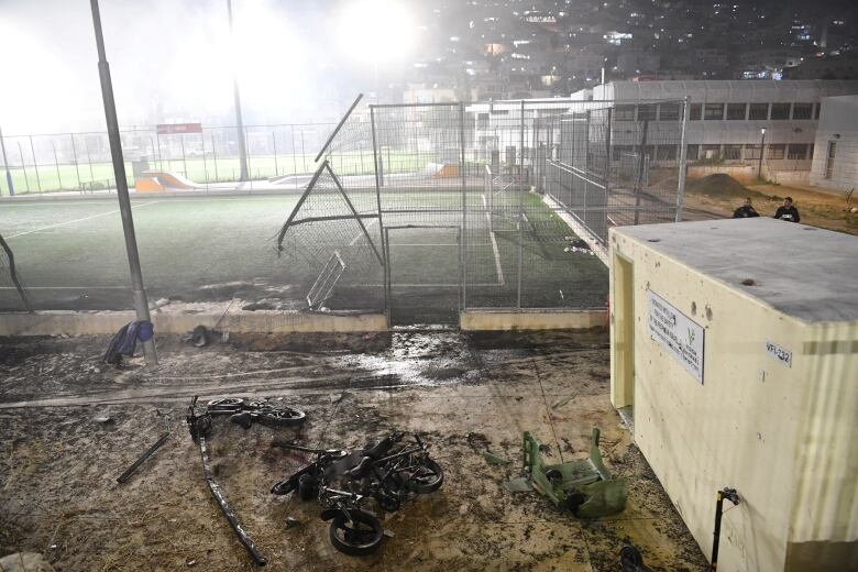 The charred remains of bikes are seen next to a damaged soccer field.