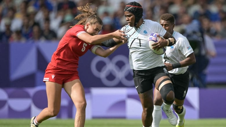 Two female rugby players are seen competing for a ball.