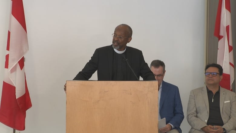 A man stands at a podium speaking.