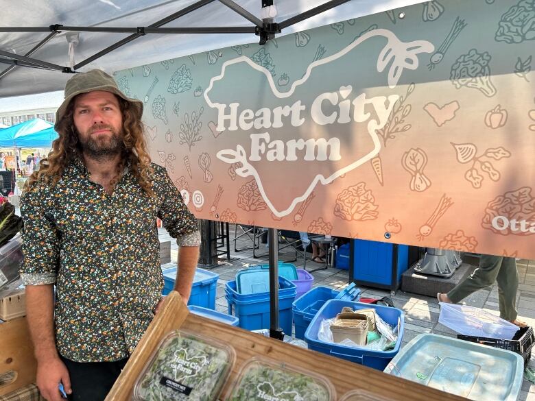 A man standing by a farm stand.