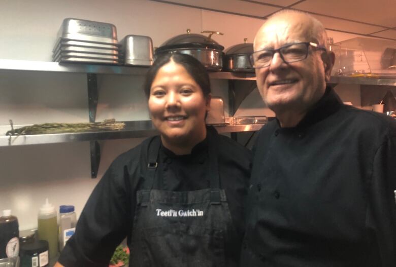 Man and woman in chef's uniform standing and smiling for picture