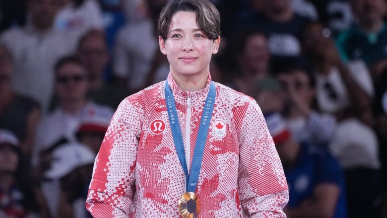 A female athlete is seen posing with a gold medal around her neck.