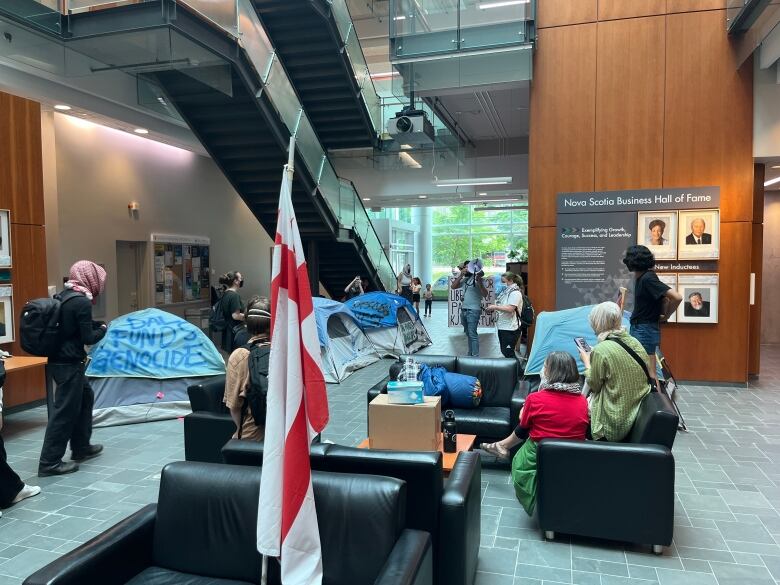 A group of tents and people are shown inside the lobby of a building.