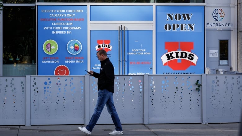 A man walks in front of a daycare storefront. 