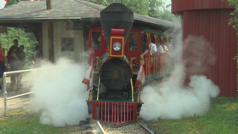 People ride in a miniature steam train.