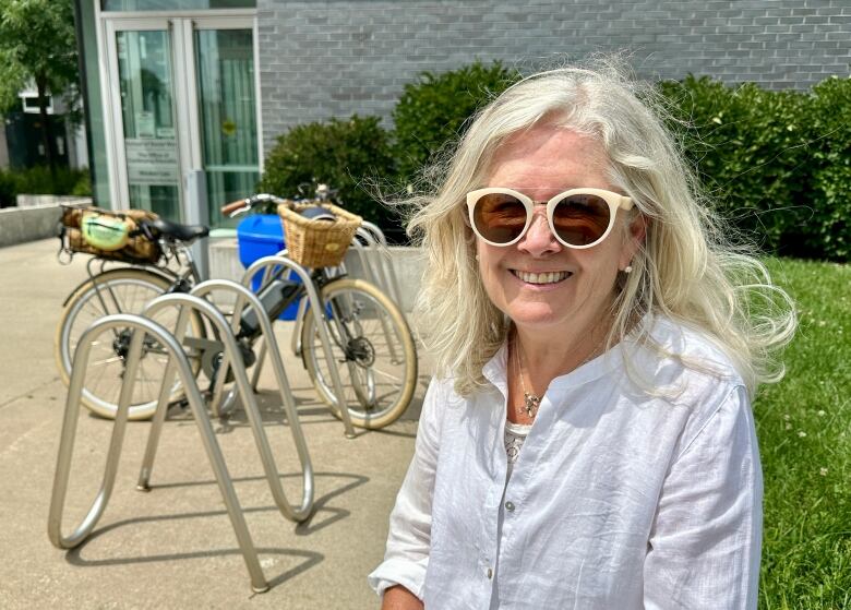 A woman sits near a bike rack.