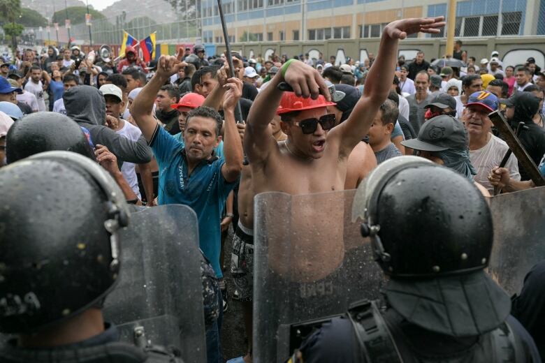 A demonstrator shouts slogans in front of police officers in Caracas on Monday.