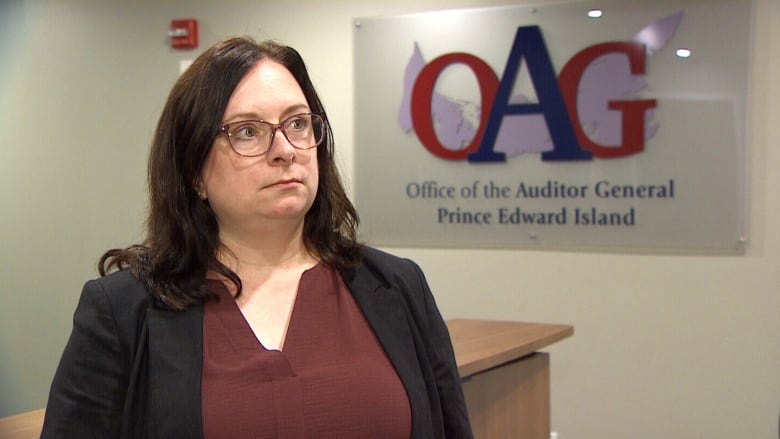 A woman in a blazer stands in an office.