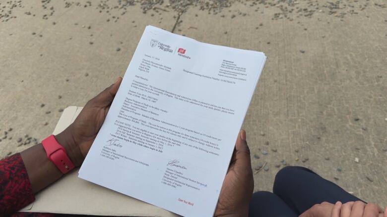 A close up of a university acceptance letter held in a woman's hands. 