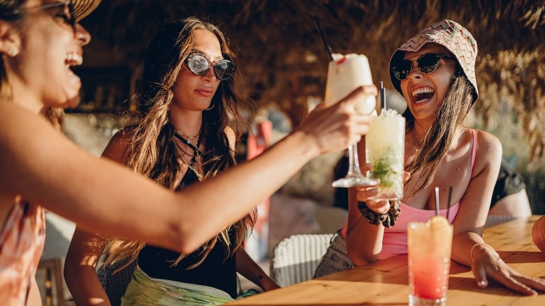 Friends in a bar on the beach where the woman in the middle has a concerned look on her face.