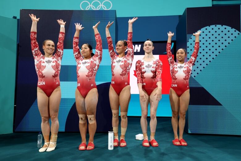 Five gymnasts wearing Canadian gear line up and pose for a picture.