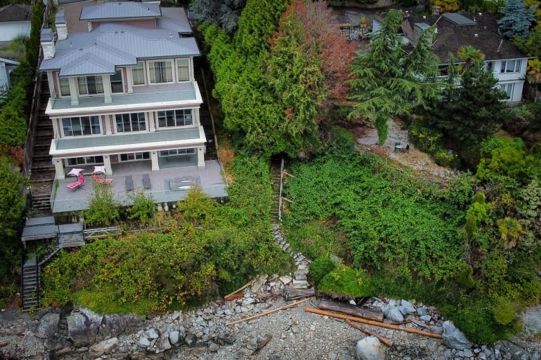 An aerial view of a path leading down a slope beside a three-storey home.