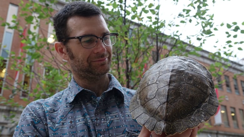 A man holds a turtle shell.