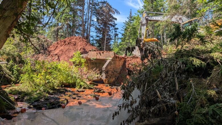 An excavator is tearing up an old concrete bridge structure 