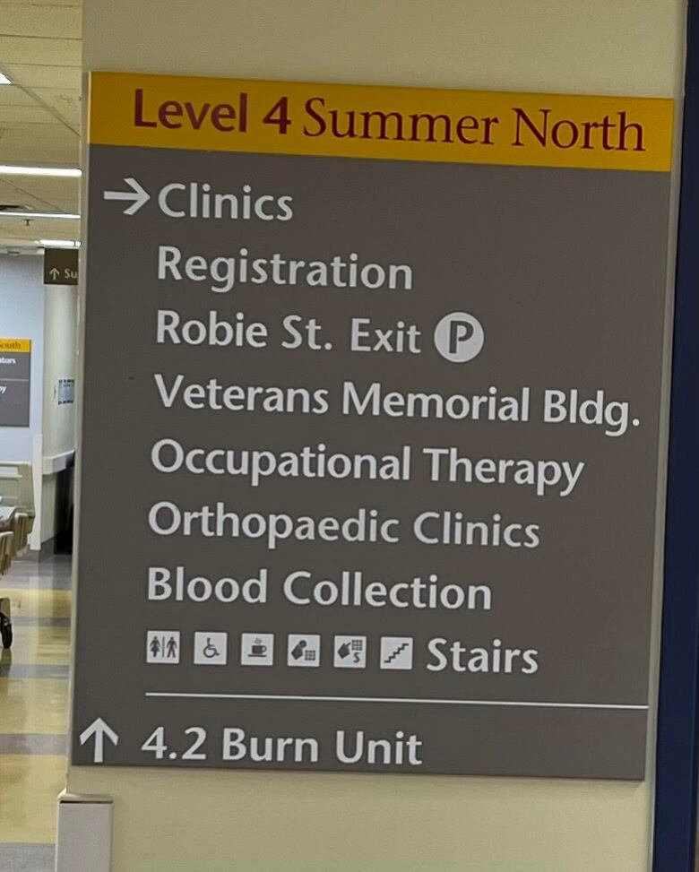 A brown and yellow sign indicating where certain places can be found, including blood collection. 