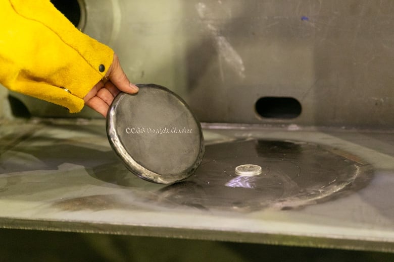 A commemorative coin is placed on a portion of the keel of CCGS Donjeck Glacier and the future coast guard ship's naming ceremony. 