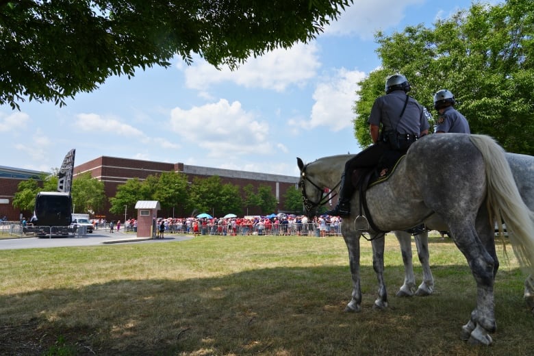 A policeman on horseback watches the lineup of people outside an arena.