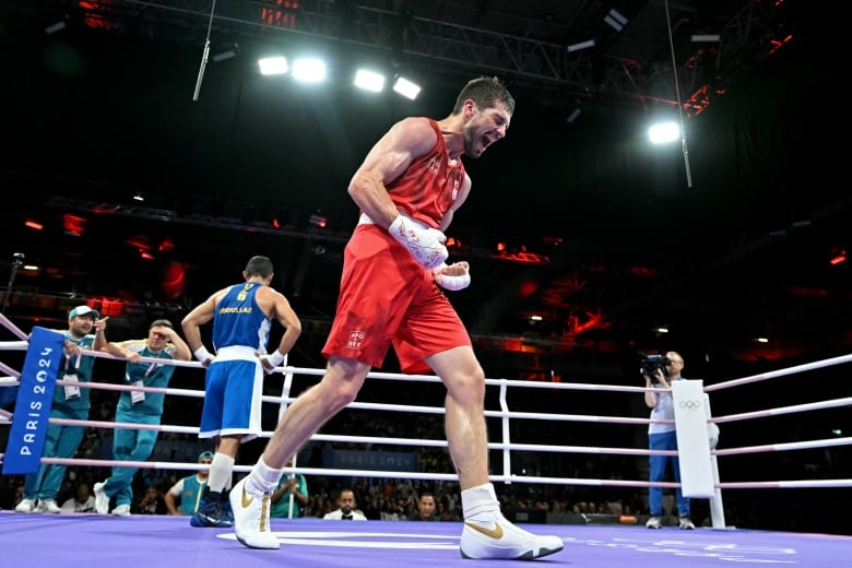 A men's boxer clenches his fists and yells in celebration