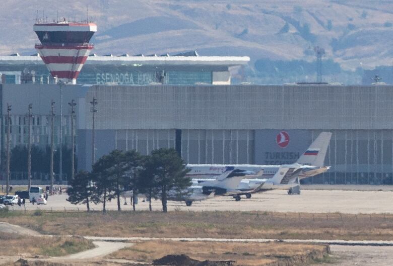 A plane with a white, blue and red Russian flag on its tail, sits on the tarmac at an airport.