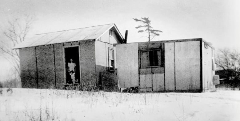 An old wooden structure standing in snow is pictured in an old photograph.