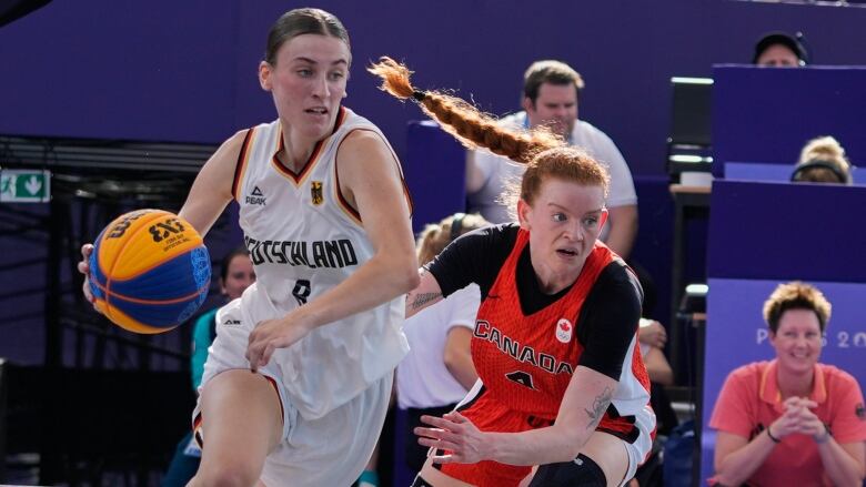 Two female basketball players are seen competing for a ball.