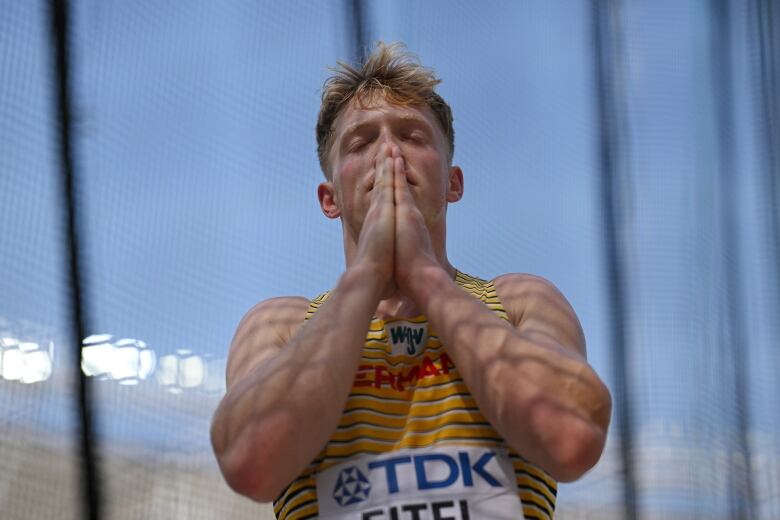 Athletic man closes his eyes and holds his hands in prayer.