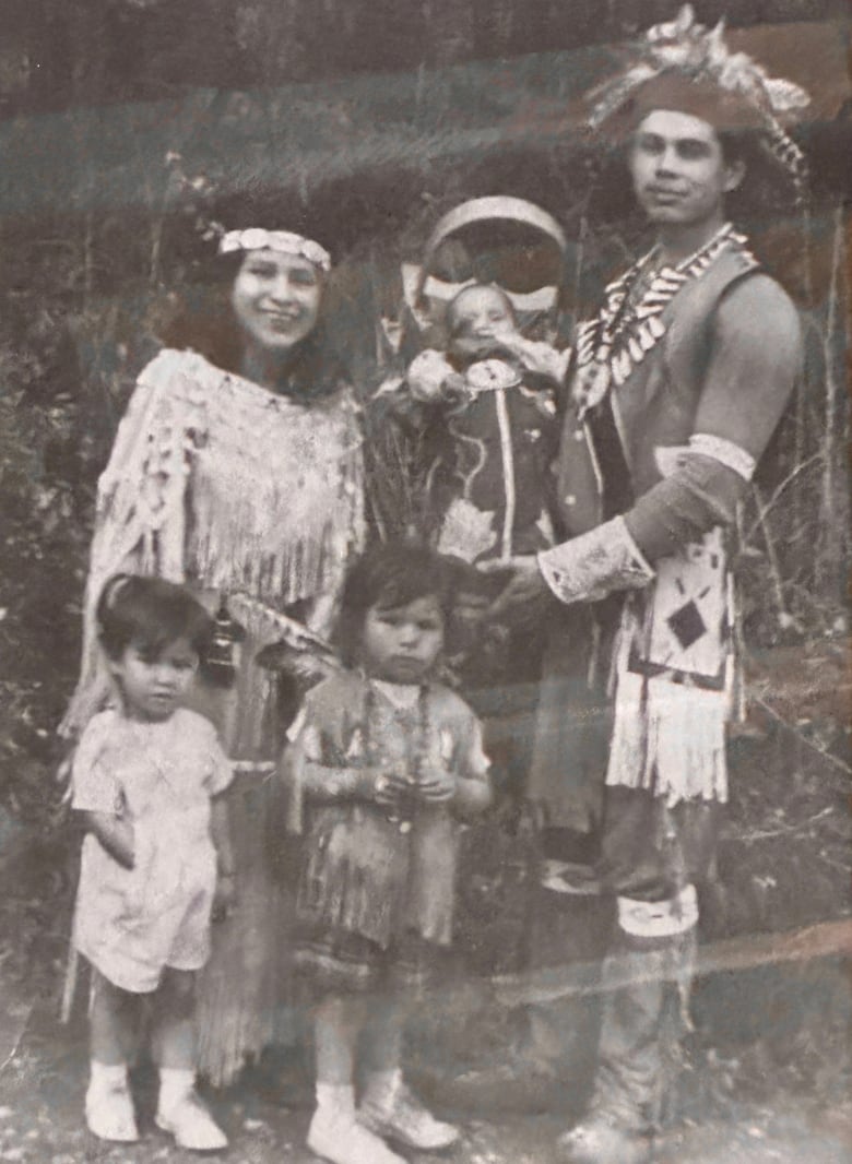 An old photo pictures a man and woman and their family wearing First Nations regalia.