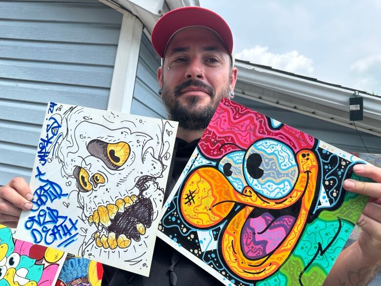 A man holds up pieces of street art.