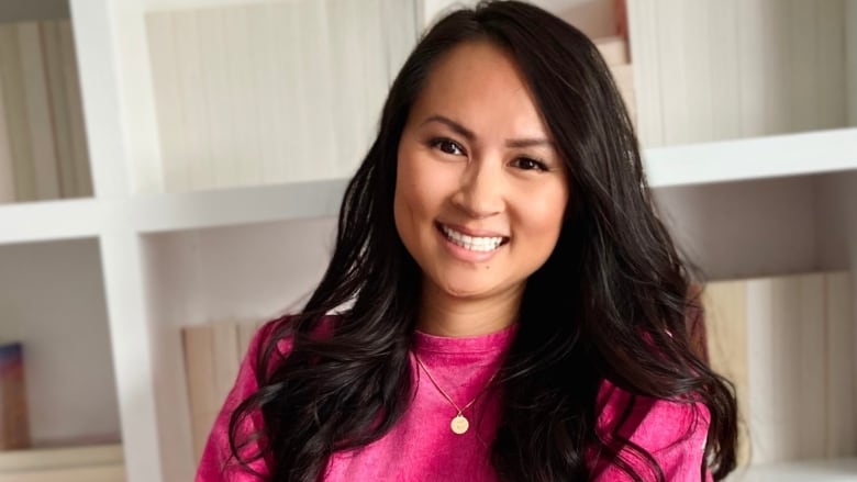 A photo of a woman with long black hair wearing a pink dress.