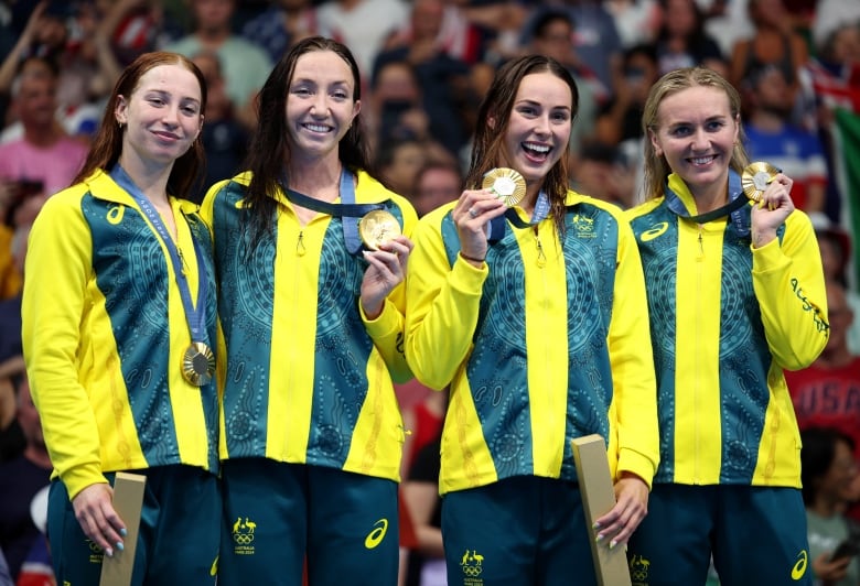 Four women wearing Australian colours hold gold medals.