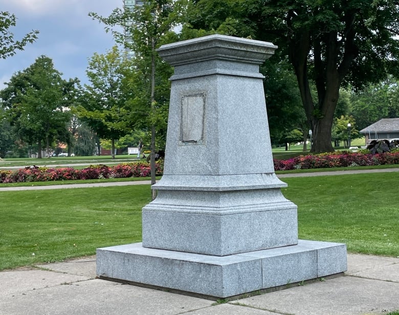 Stone monument in a park with obvious signs that a plaque is missing from it