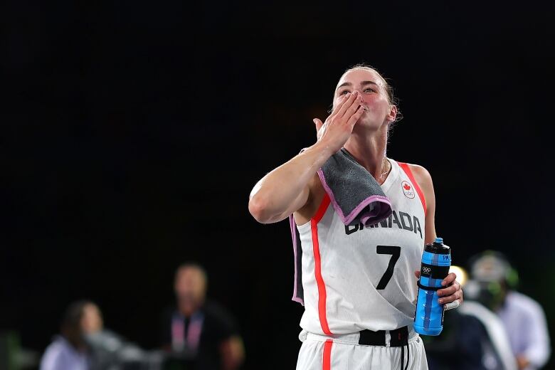 A women's basketball player sends a kiss to the crowd. 