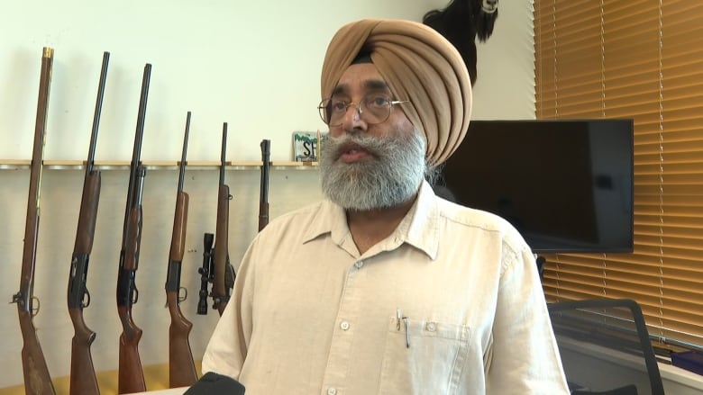 A man in turban getting interviewed with firearms in the background.