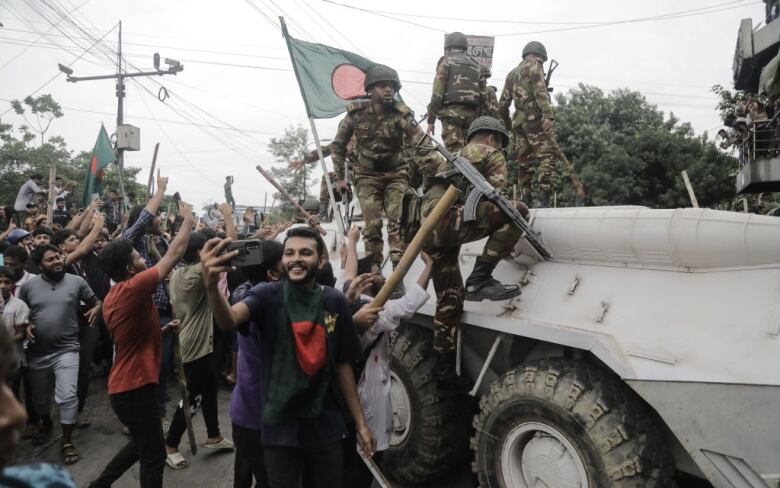 People stand near a military vehicle to celebrate.