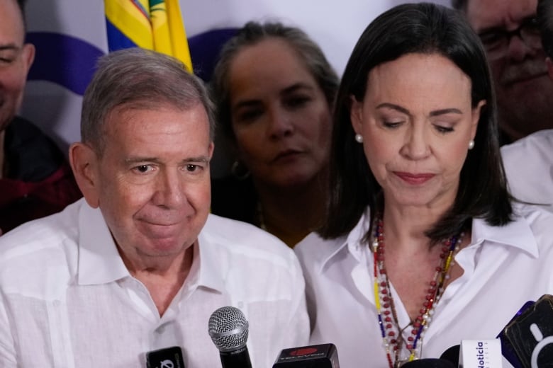 Two people stand in front of microphones.