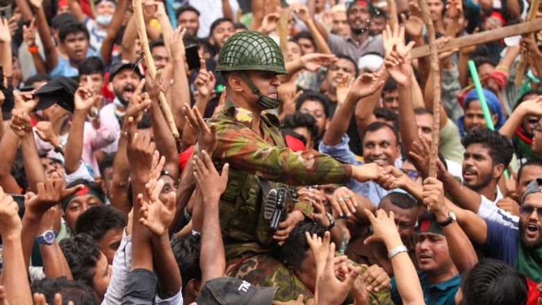 A soldier shakes hands with one of several protesters.