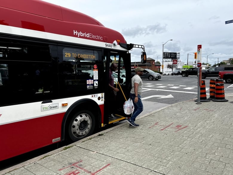 Two men board off of a TTC bus. 