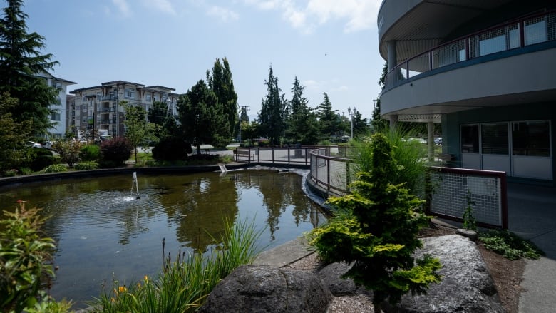 A large decorative water pond sits in front of a three-storey community centre.