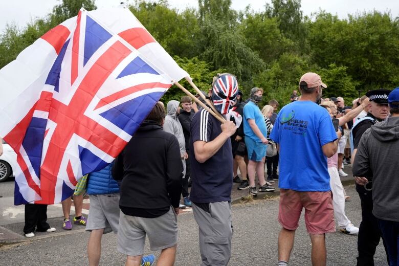 A man in a group of protesters wears a mask and holds a flag.