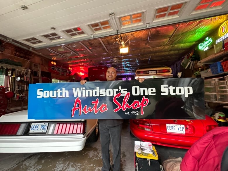 A man holds a sign in front of two cars