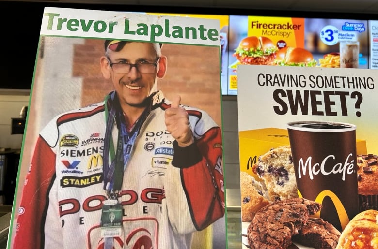 A picture of a smiling man standing in a McDonald's next to advertisements for fast food.