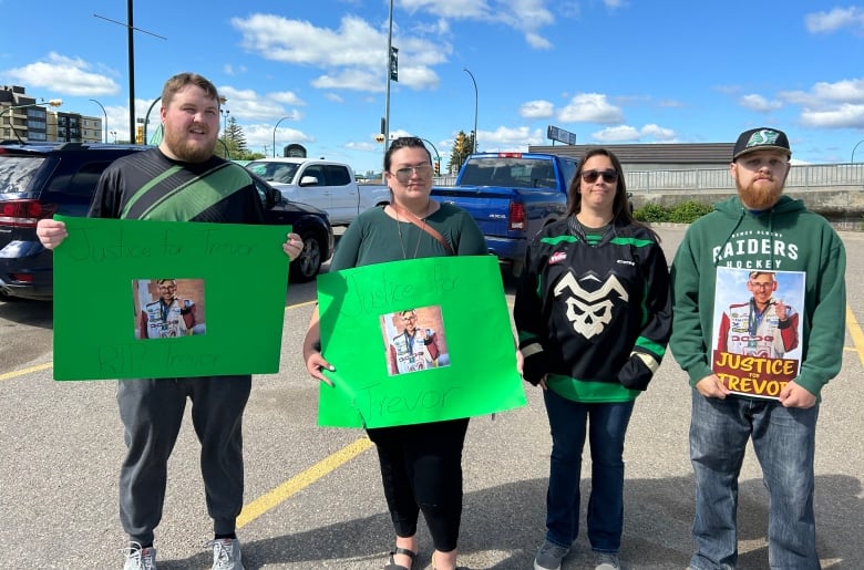 Four people, three of them holding handmade signs, pose for a photo.