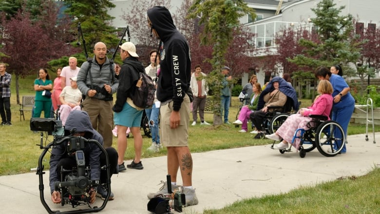 A group of people are seen on a cloudy day in Calgary at a movie set. 