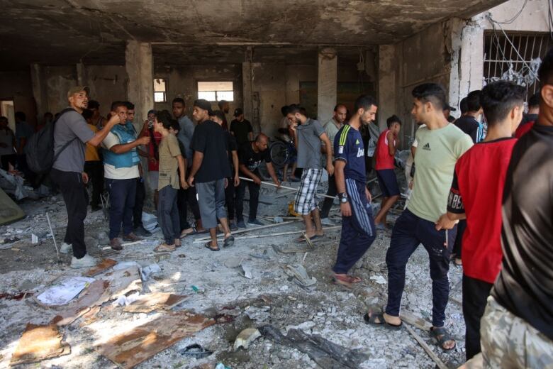 Palestinians in Gaza check the damage at a school.