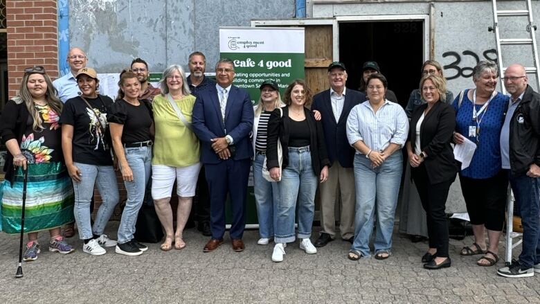 A group of people standing in front of a sign that says Cafe 4 Good.