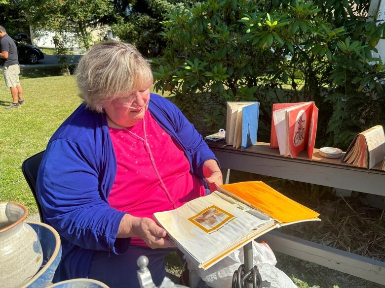 A woman opens a book that is wet.